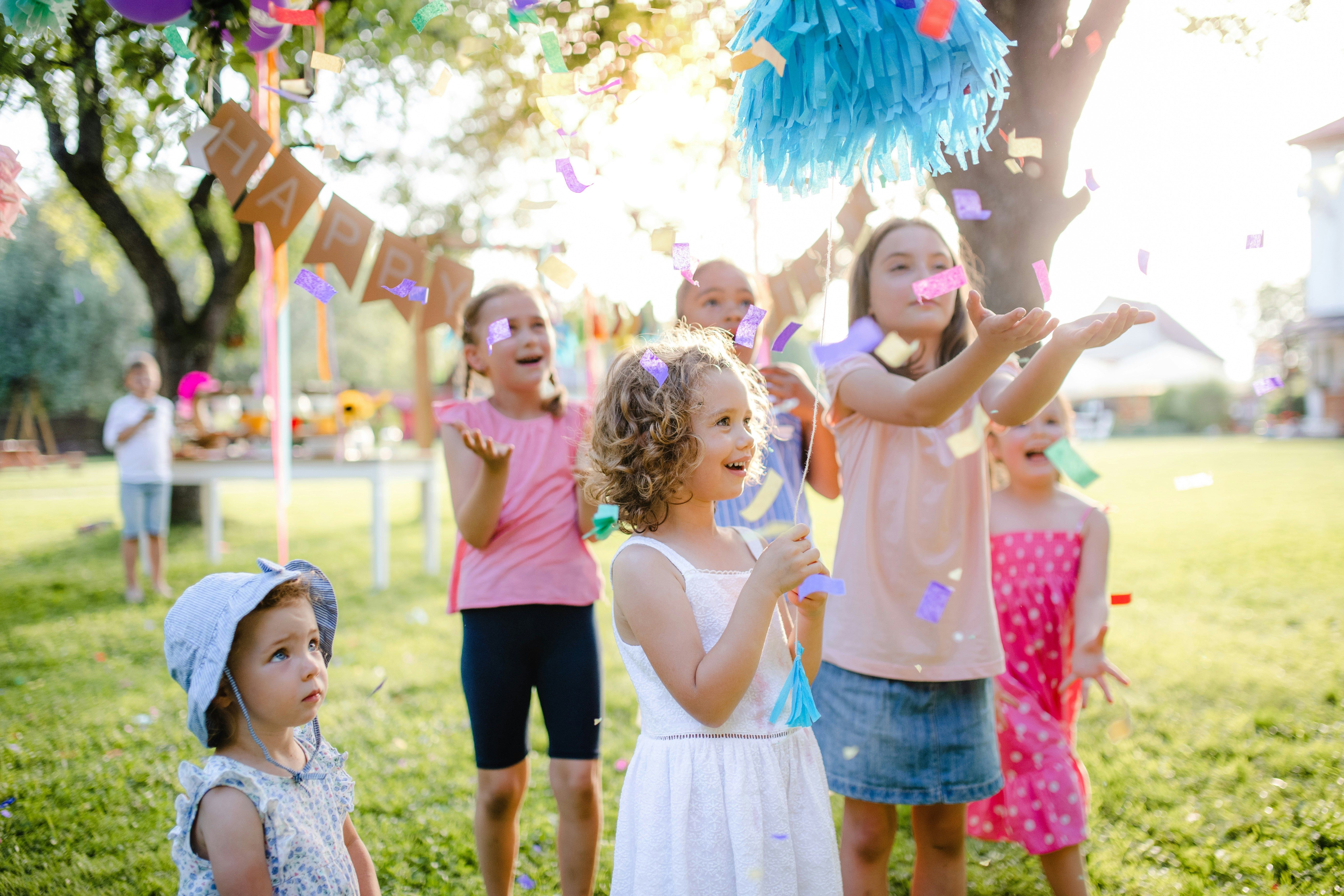 Children celebrating a birthday in a decorated garden with tables and chairs