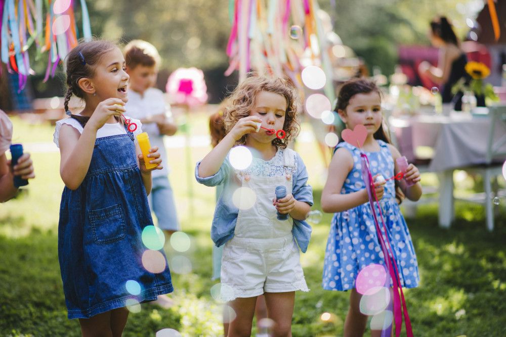 Children playing games in a garden near decorated tables and chairs