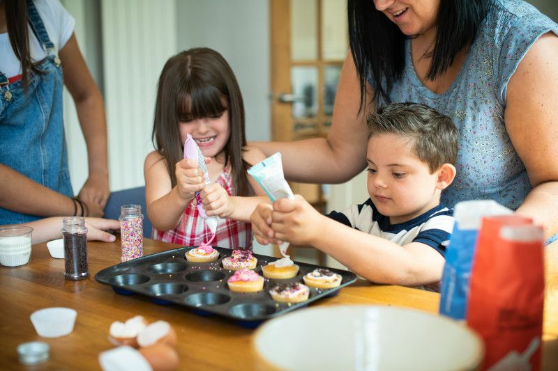 Children decorating cupcakes with colorful icing and sprinkles