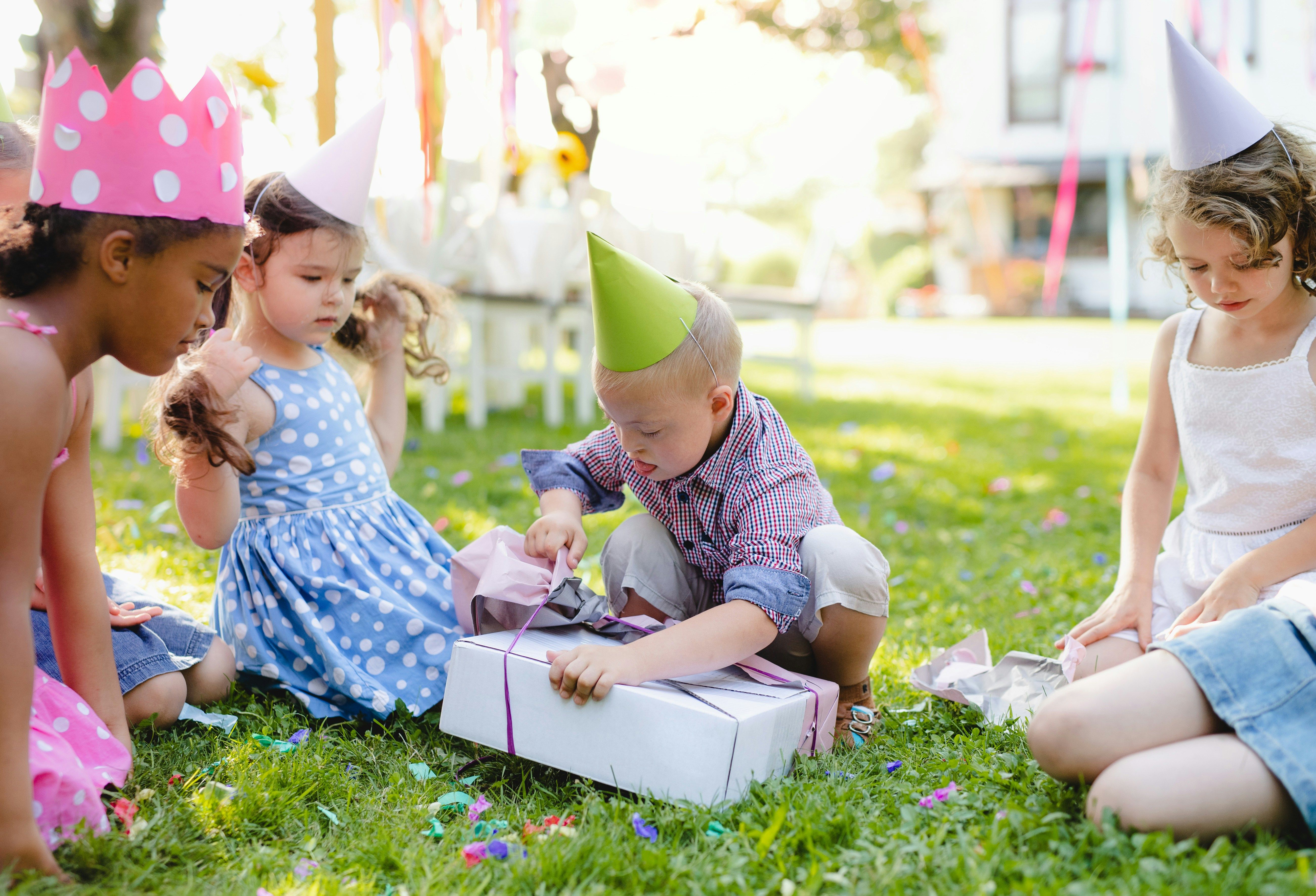Children sitting in a circle outdoors passing a wrapped present