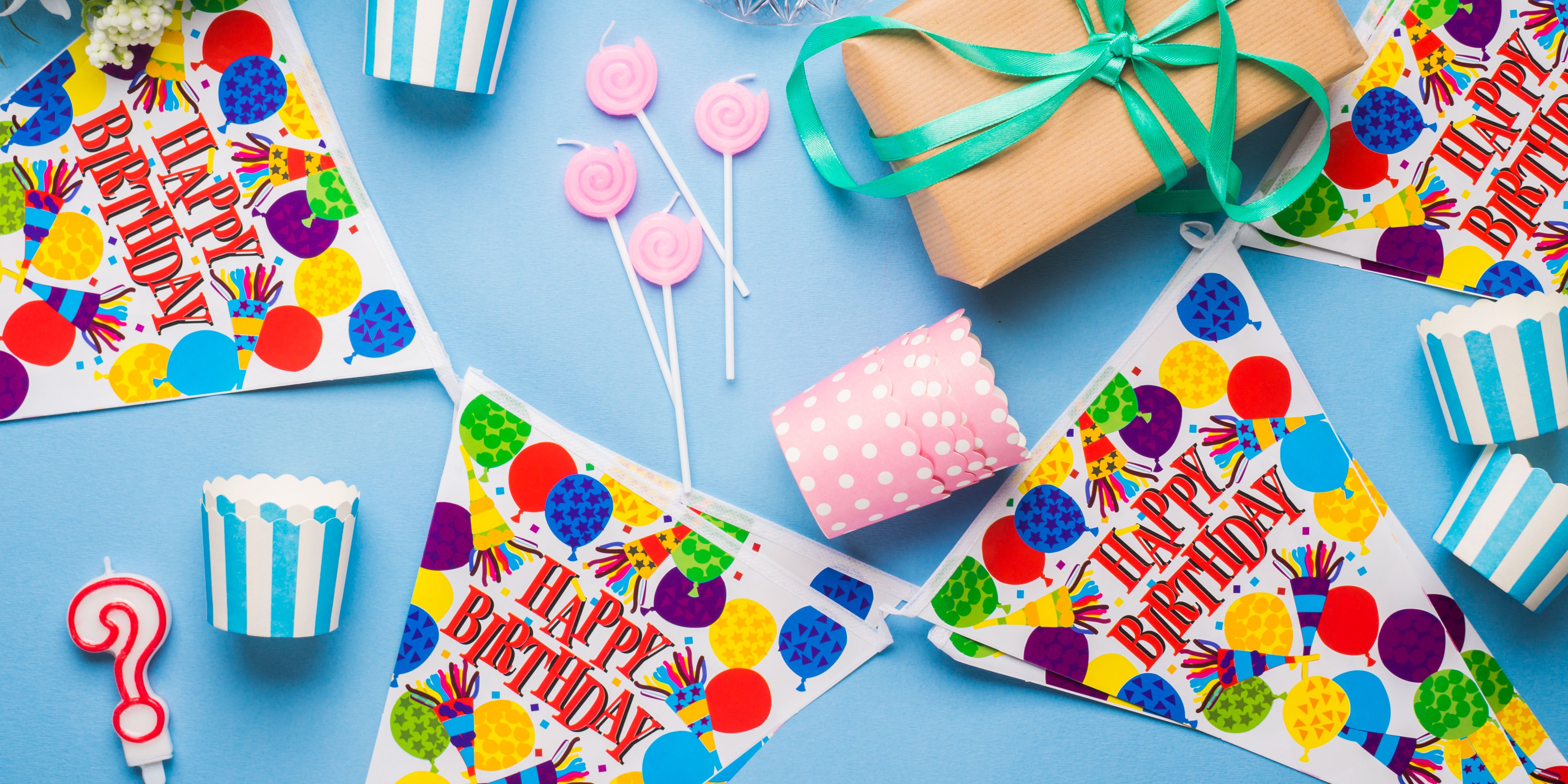 Children gathered around a colorful birthday cake with balloons in the background