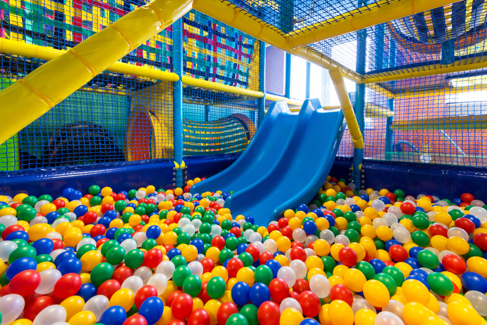 Children playing in an indoor playground with slides and ball pit